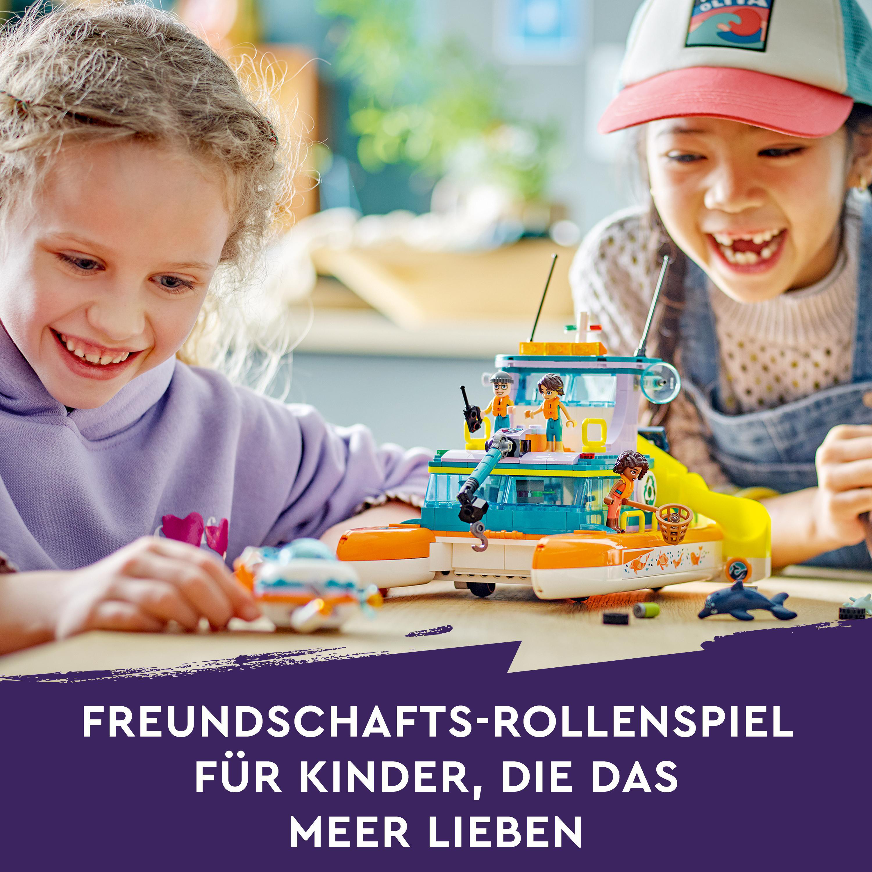 Zwei Mädchen spielen mit einem Lego-Boot. Das Boot ist orange und blau.