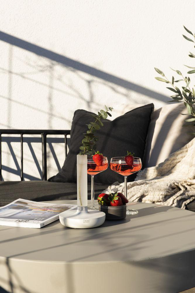 Zwei Gläser mit roten Getränken und Erdbeeren auf einem Tisch. Hintergrund ist eine weiße Wand.