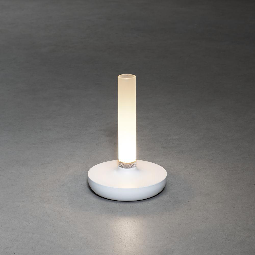 Weiße, runde Tischlampe mit heller, zentraler Lichtsäule auf grauem Boden.