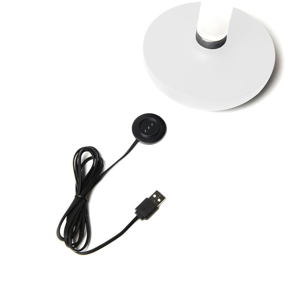 Weißer Lampensockel mit schwarzer Ladestation und USB-Kabel. Weißer Hintergrund. Draufsicht.