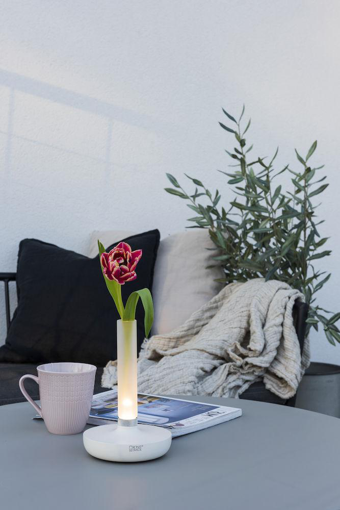 Ein Tisch mit Vase, Blume, Zeitschrift und rosa Becher.