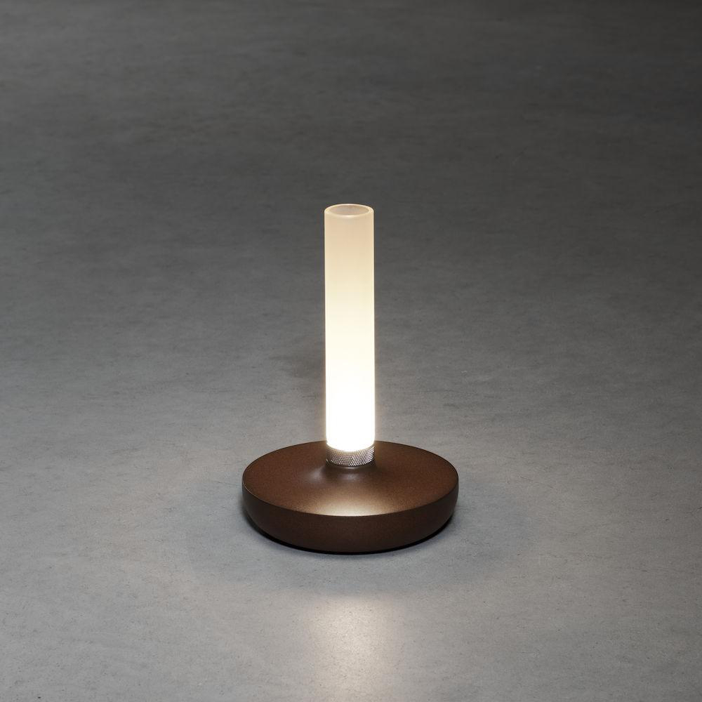 Braune Lampe mit leuchtendem Oberteil auf grauer Oberfläche.