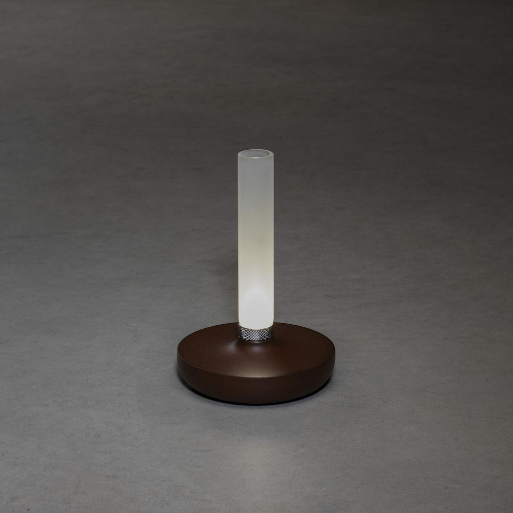 Ein brauner, kreisförmiger Sockel mit einer weißen, beleuchteten, vertikalen Röhrenlampe darauf.