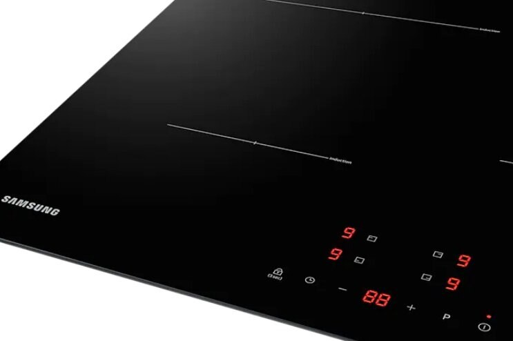Zbliżenie czarnej płyty indukcyjnej Samsung z czerwonym wyświetlaczem cyfrowym, pokazującym pola indukcyjne.