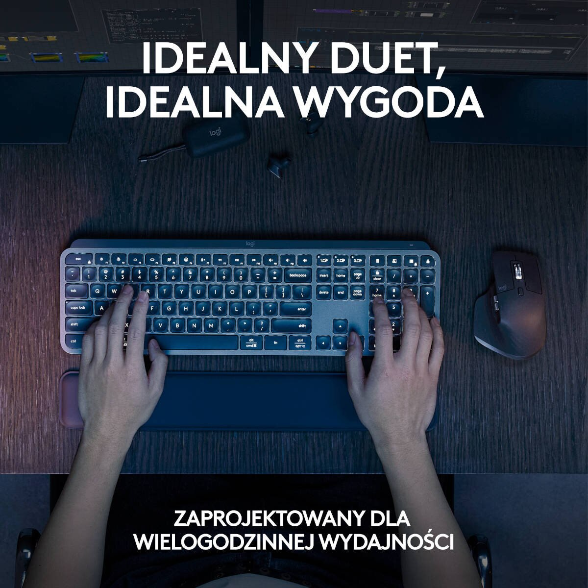 Osoba korzystająca z klawiatury i myszy na biurku z dwoma monitorami.