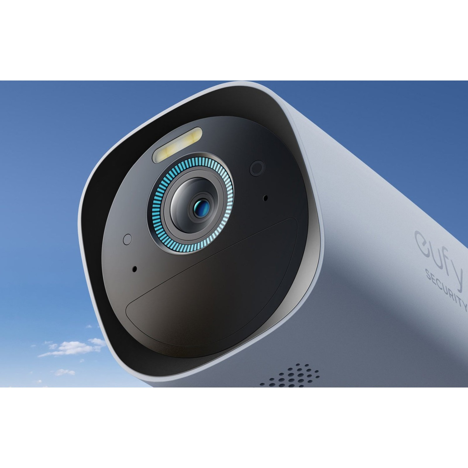 A security camera with a blue sky background. The camera is gray and black.