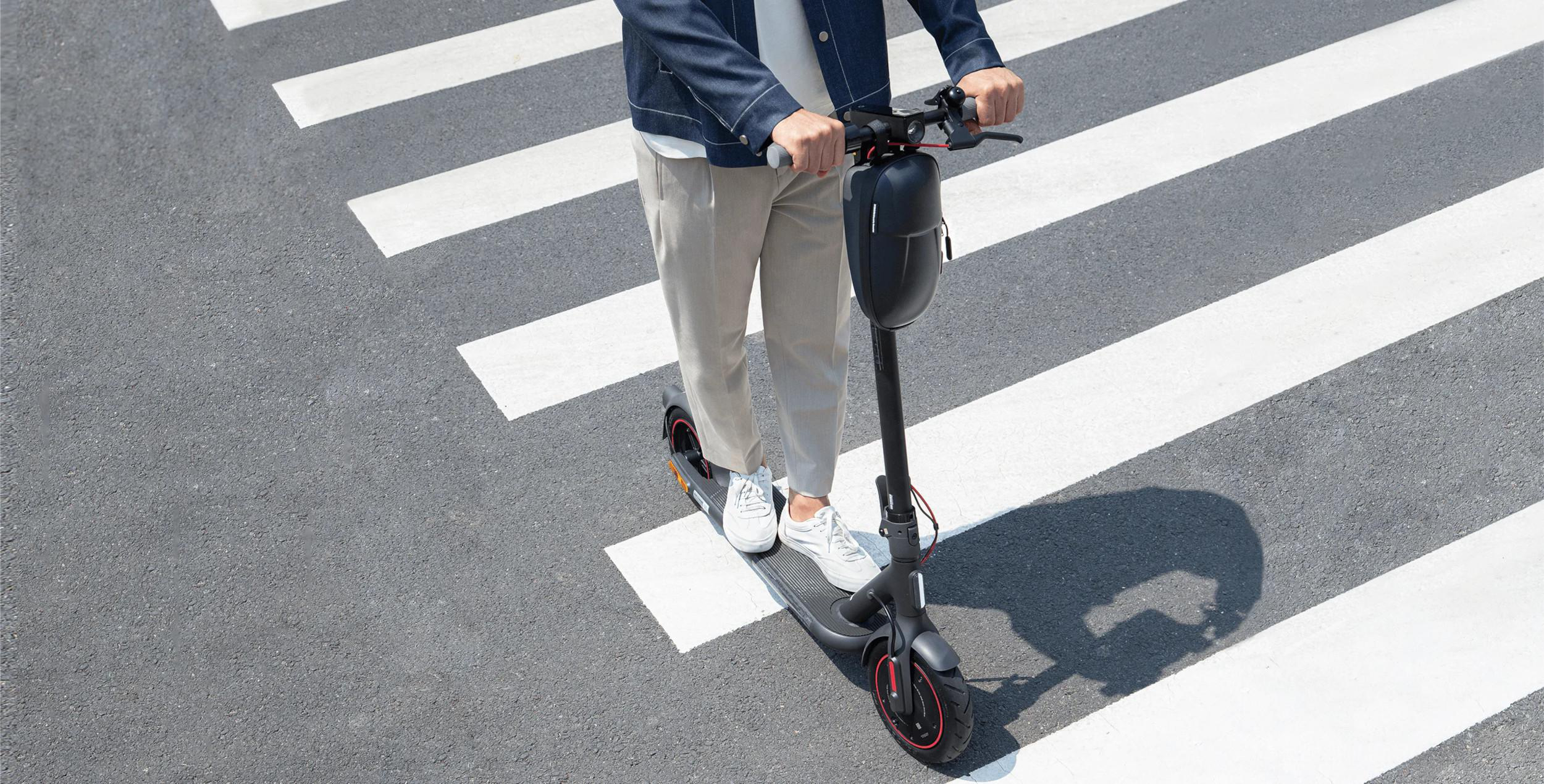 Person auf einem Roller überquert einen Zebrastreifen. Zebrastreifen sind sichtbar.