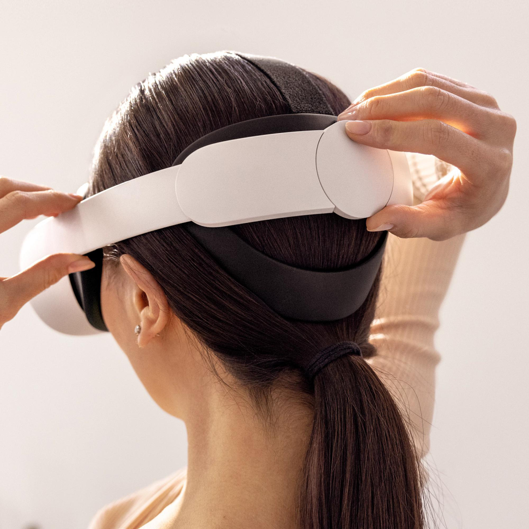 Eine Frau, die ein weißes VR-Headset aufsetzt, von hinten gesehen.