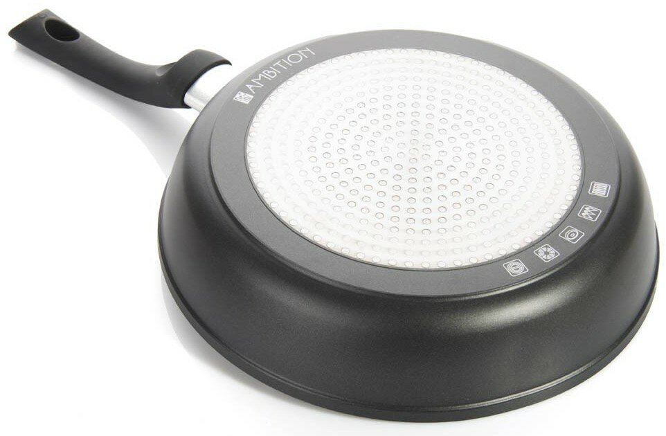 Spód czarnej patelni z białą, kropkowaną powierzchnią.