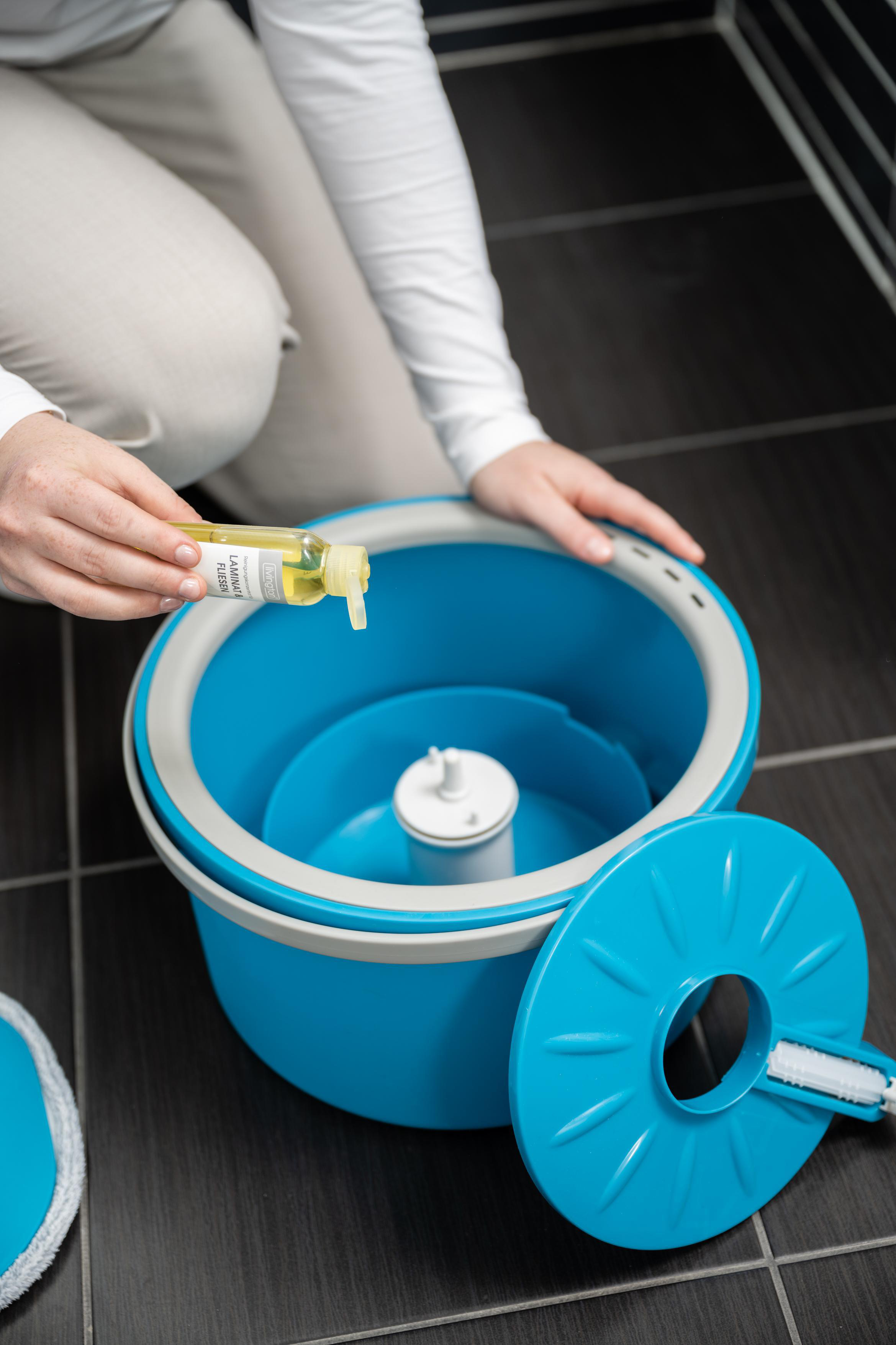 Person gießt Reinigungslösung in einen blauen Eimer.