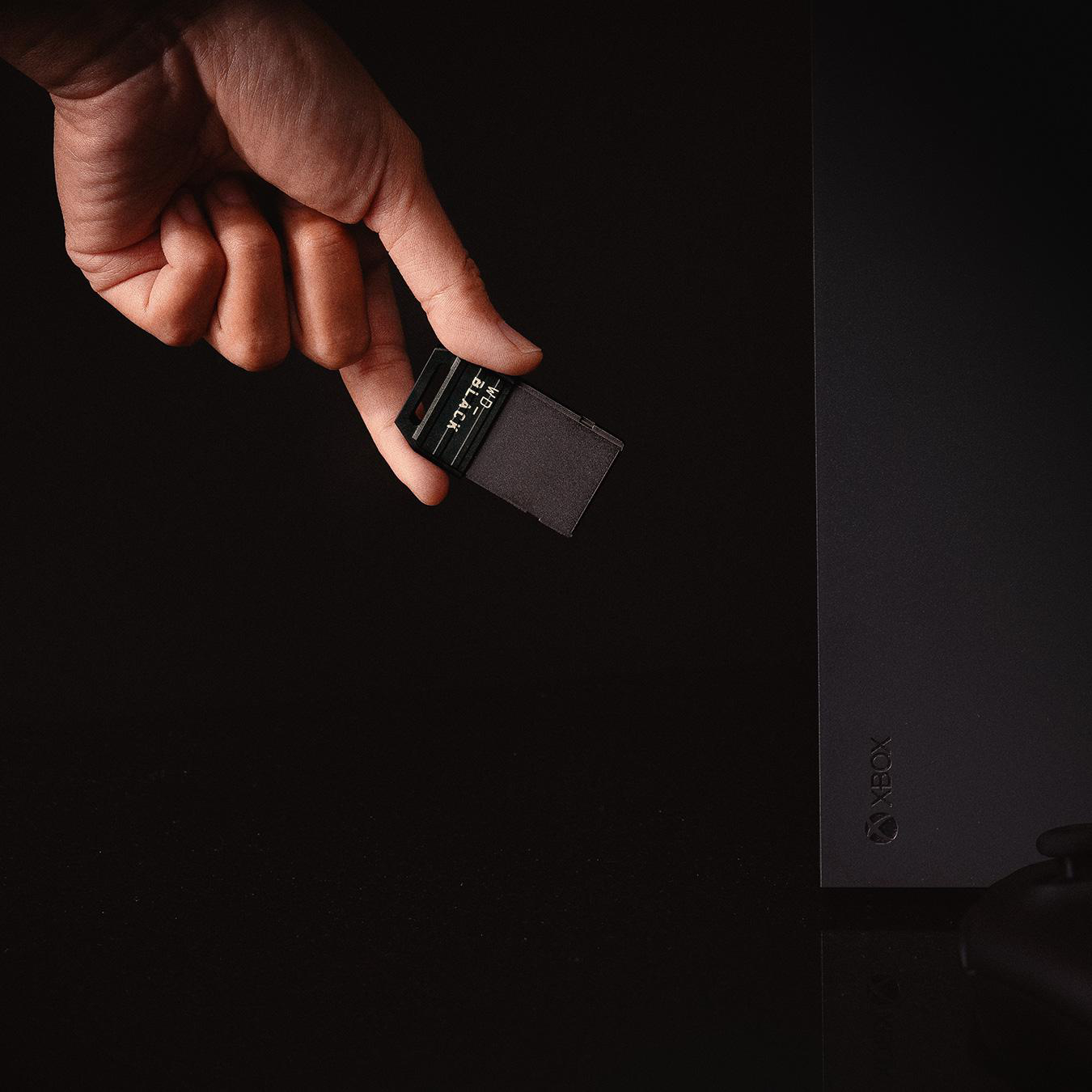 Eine Hand hält ein kleines schwarzes WD_BLACK-Speichergerät vor schwarzem Hintergrund.