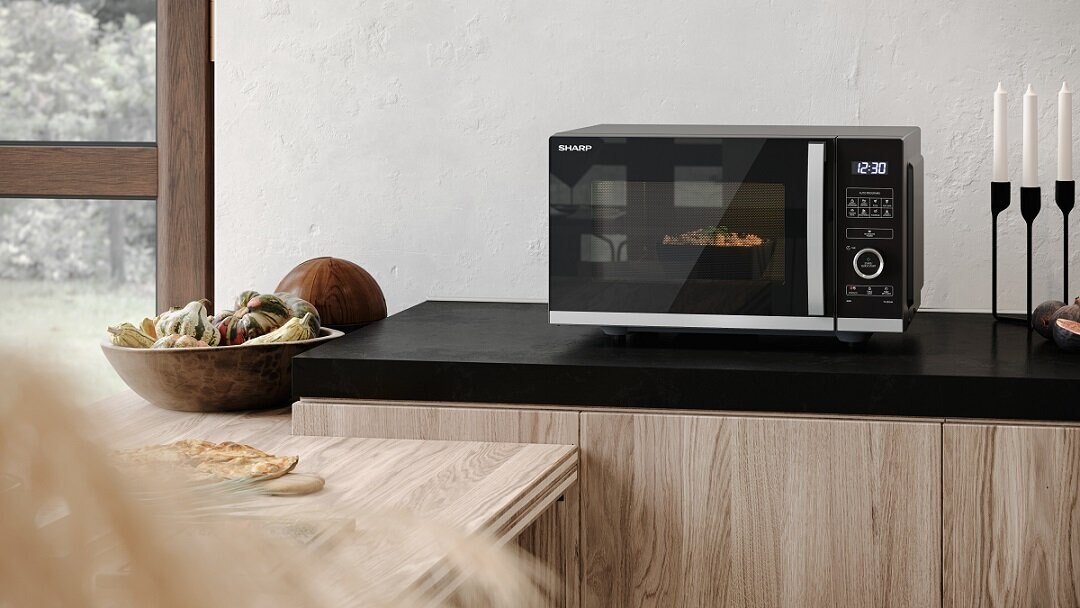 Mikrofalówka Sharp na blacie z misą z dyniami. Świece i figi są w pobliżu. Pizza leży na blacie poniżej.