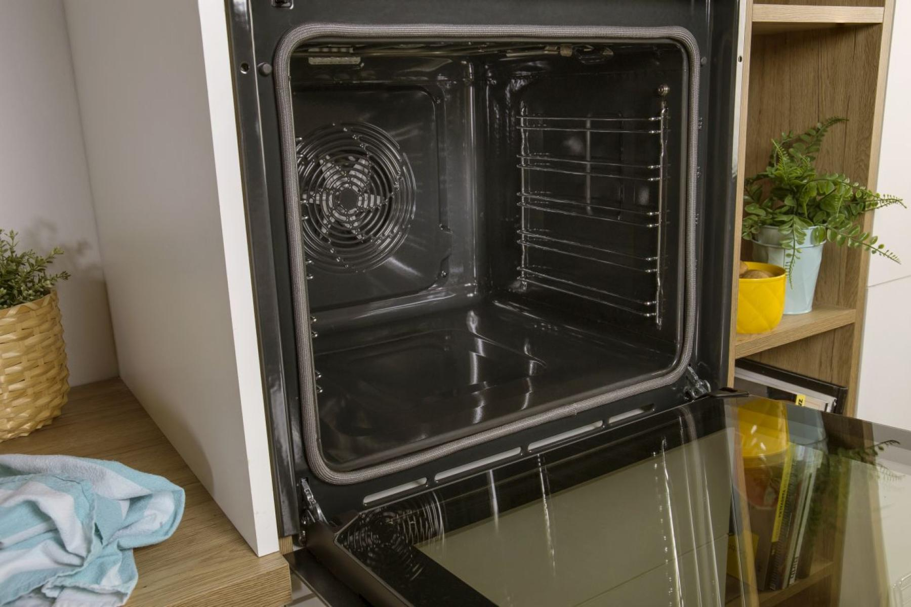 Egy nyitott sütő fémráccsal és ventilátorral. Az ajtó nyitva van.