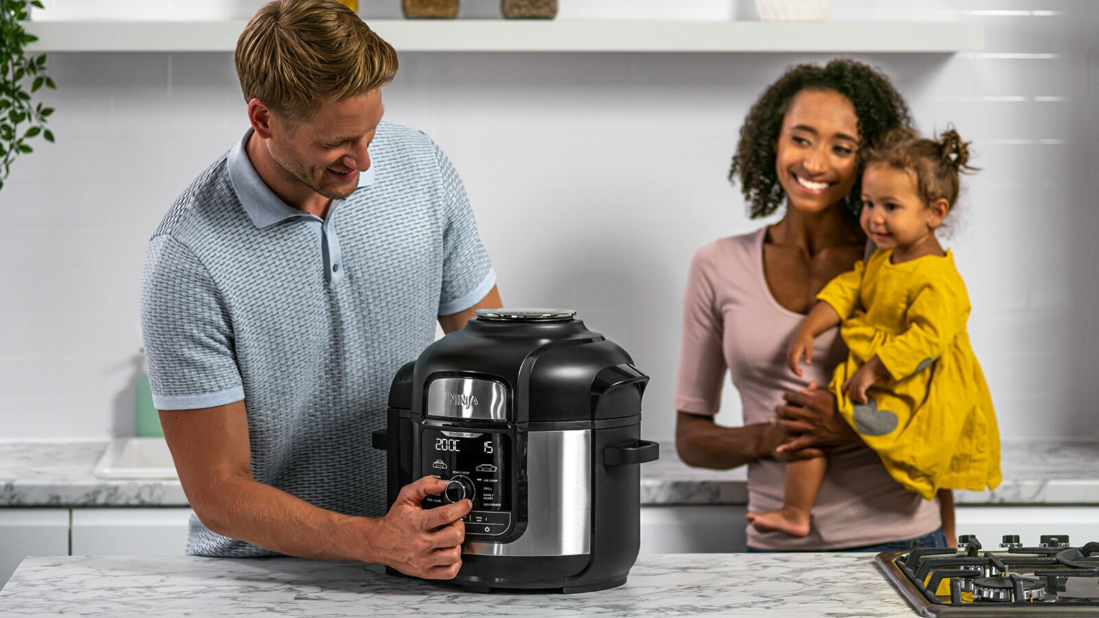 Rodzina gotująca z multicookerem Ninja. Mężczyzna i kobieta wchodzą w interakcje z urządzeniem.