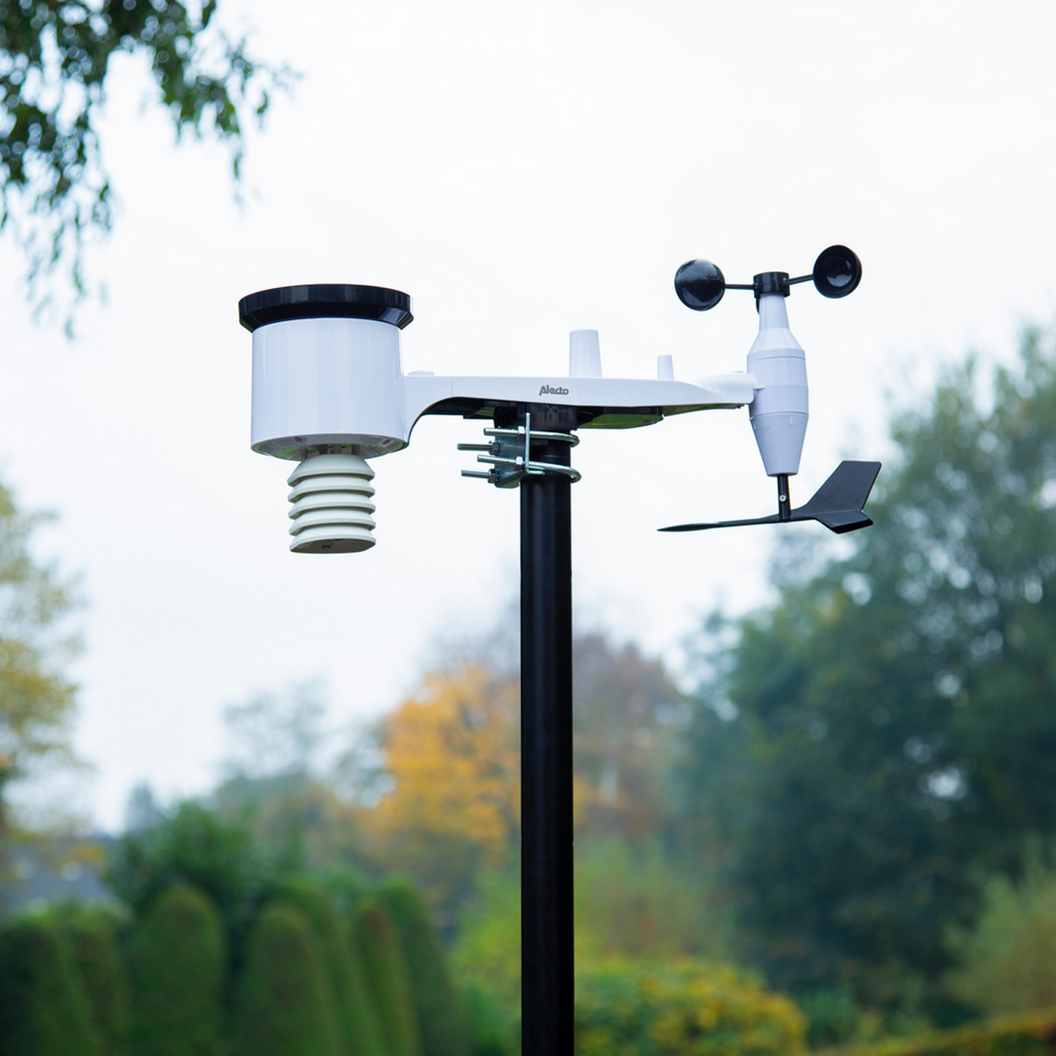 Weather station. White body, sensors, and a black pole. Installed outdoors.