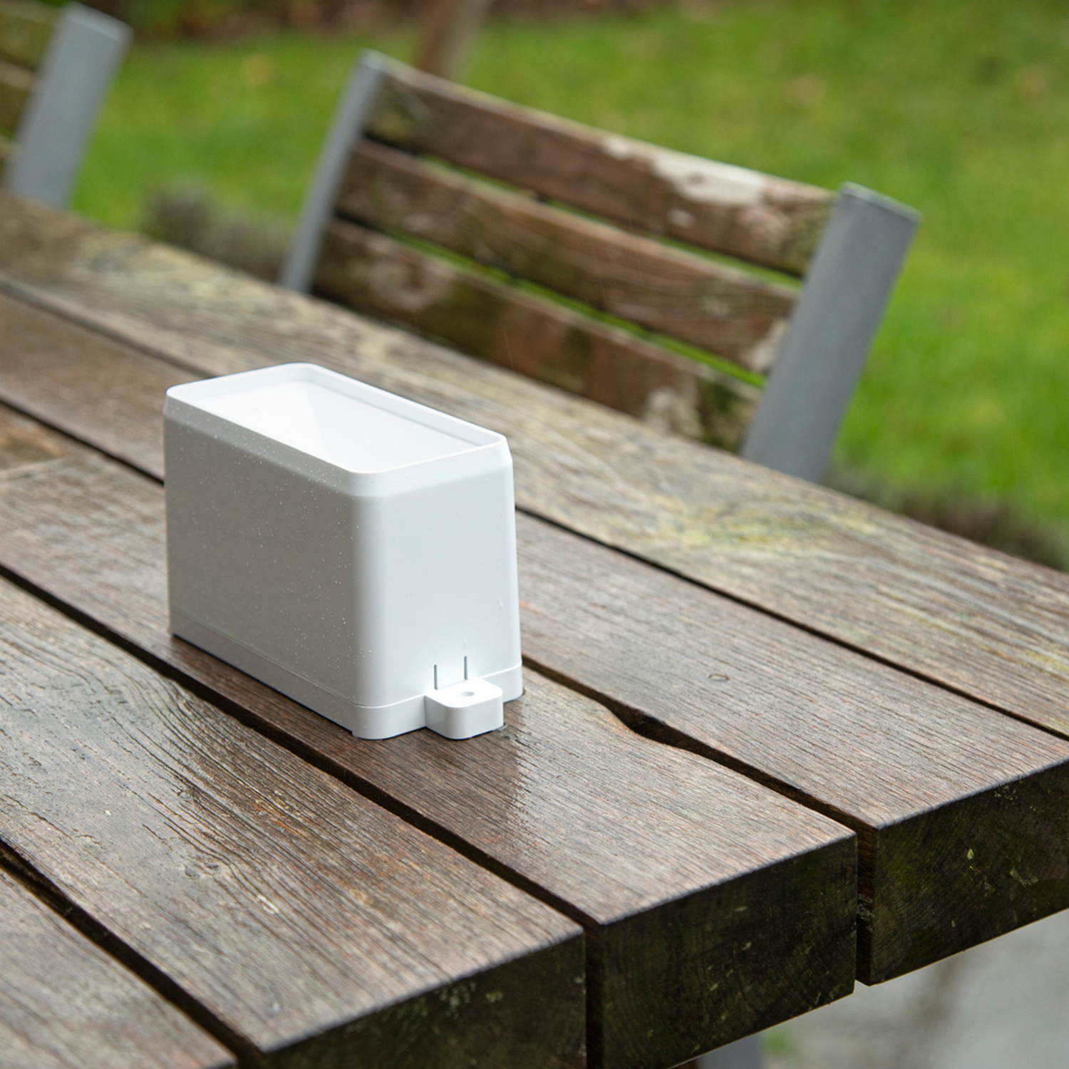 White weather station on a wooden table. The table is wet.