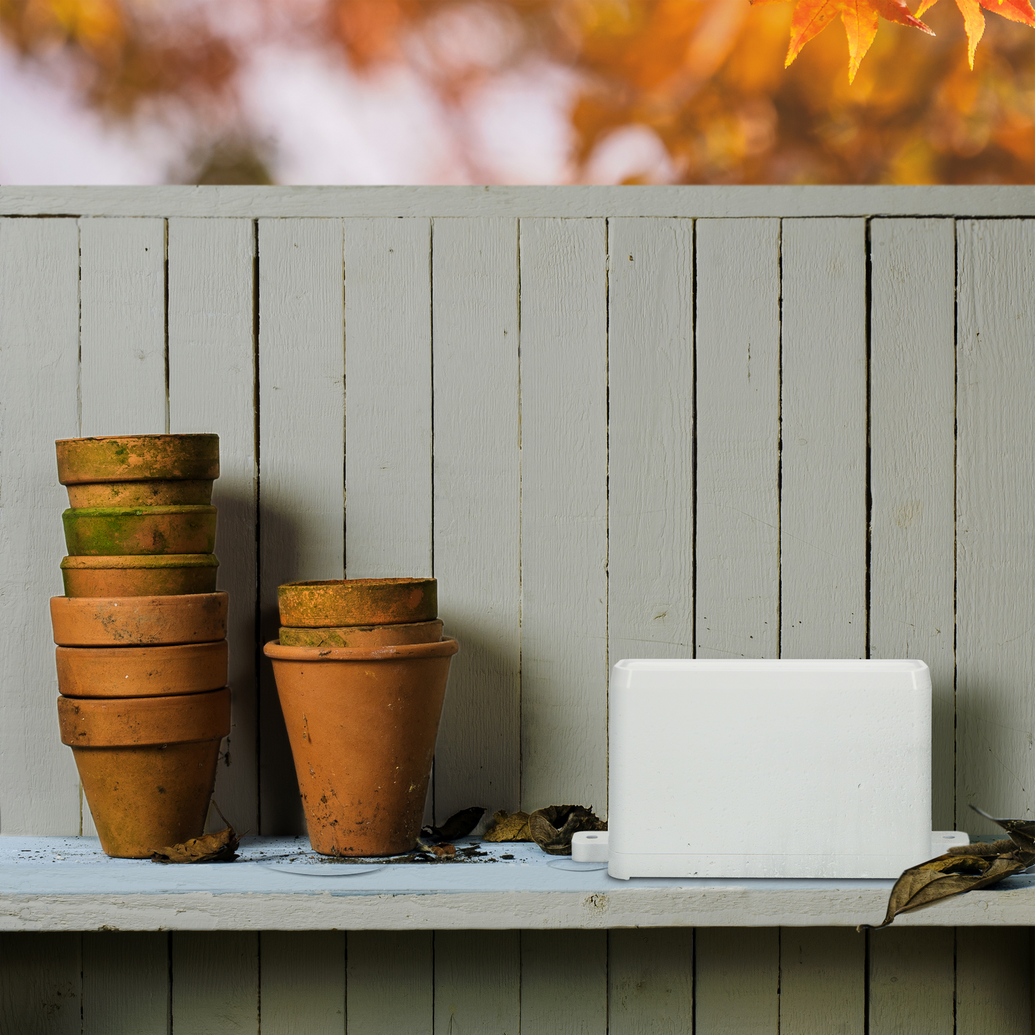 Pots on a shelf, a white device, and a wooden fence in the background.