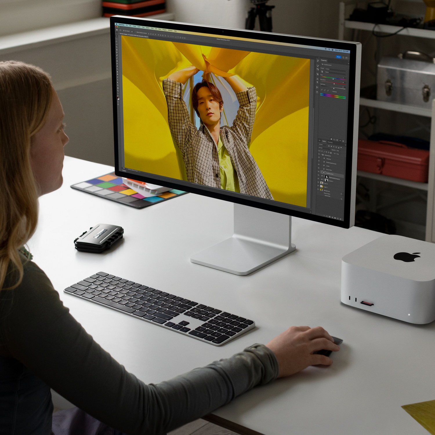Vrouw aan bureau computer gebruikend, afbeelding bewerkend op monitor, met Mac Studio en toetsenbord.