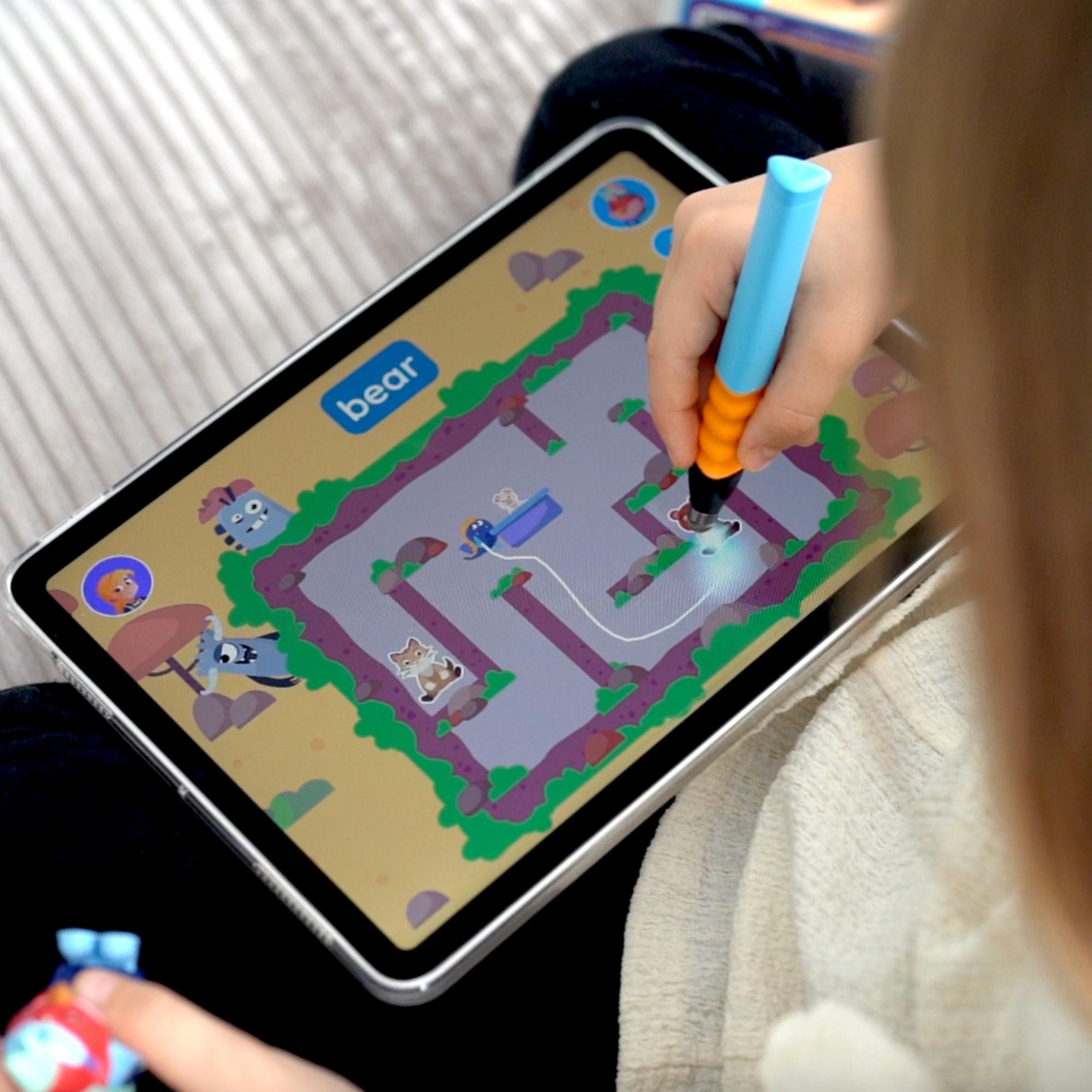 Ein Kind benutzt ein Tablet mit einem Stift. Das Tablet zeigt ein Spiel mit Grafiken.