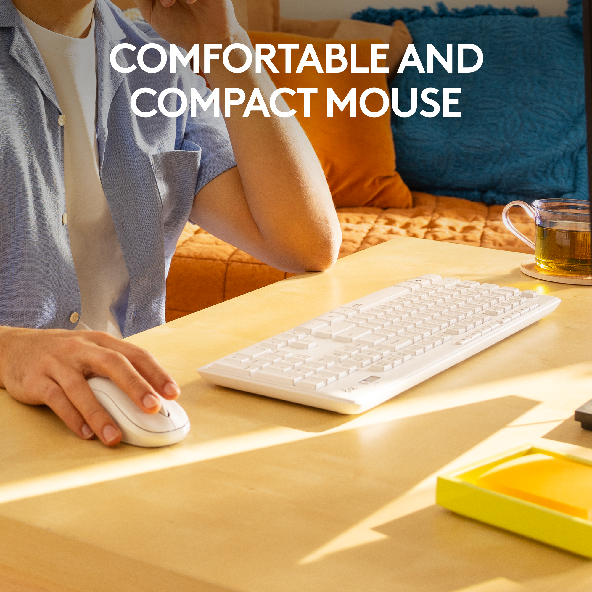Une personne utilise une souris et un clavier blancs sur un bureau en bois clair.