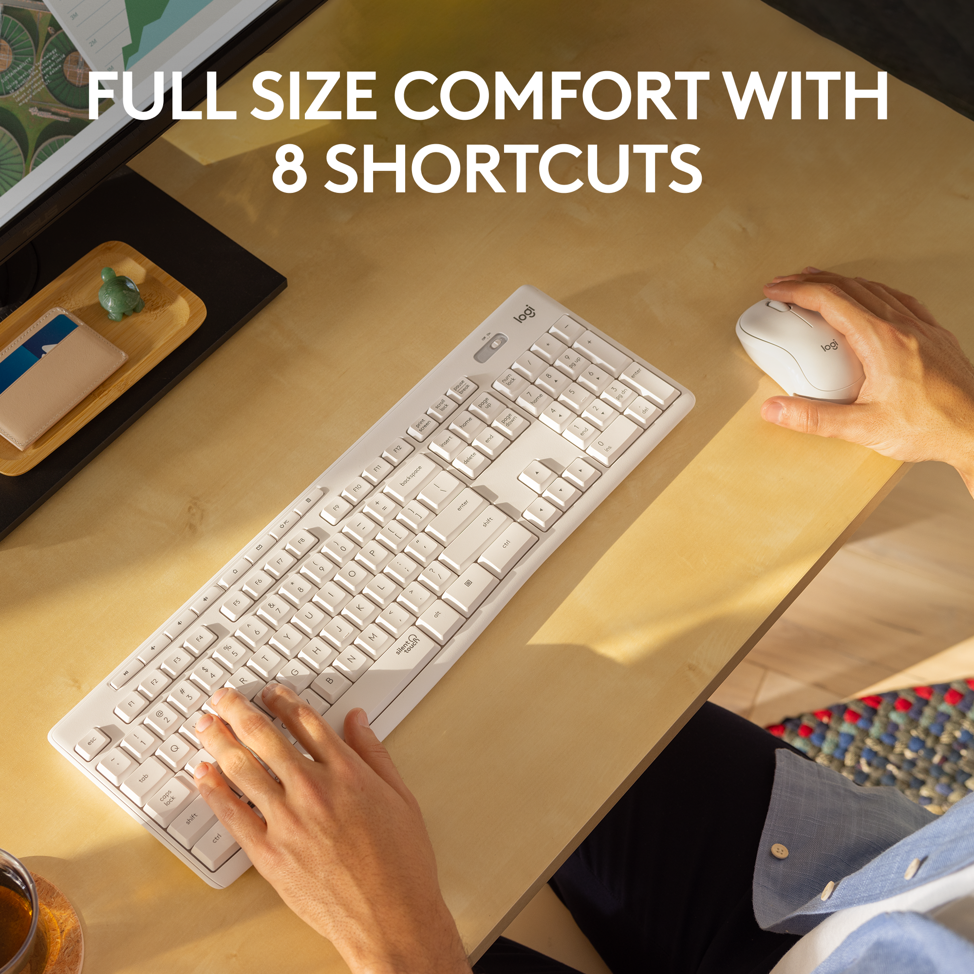 Un clavier blanc avec une souris et une tasse sur un bureau en bois.