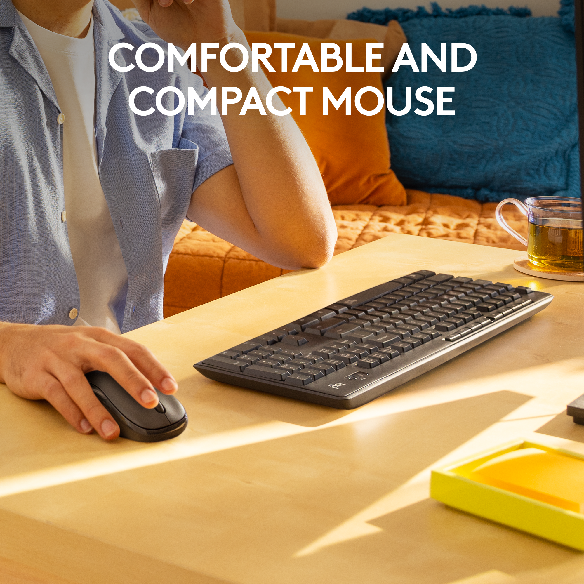 Personne utilisant une souris et un clavier sans fil noirs sur un bureau en bois.