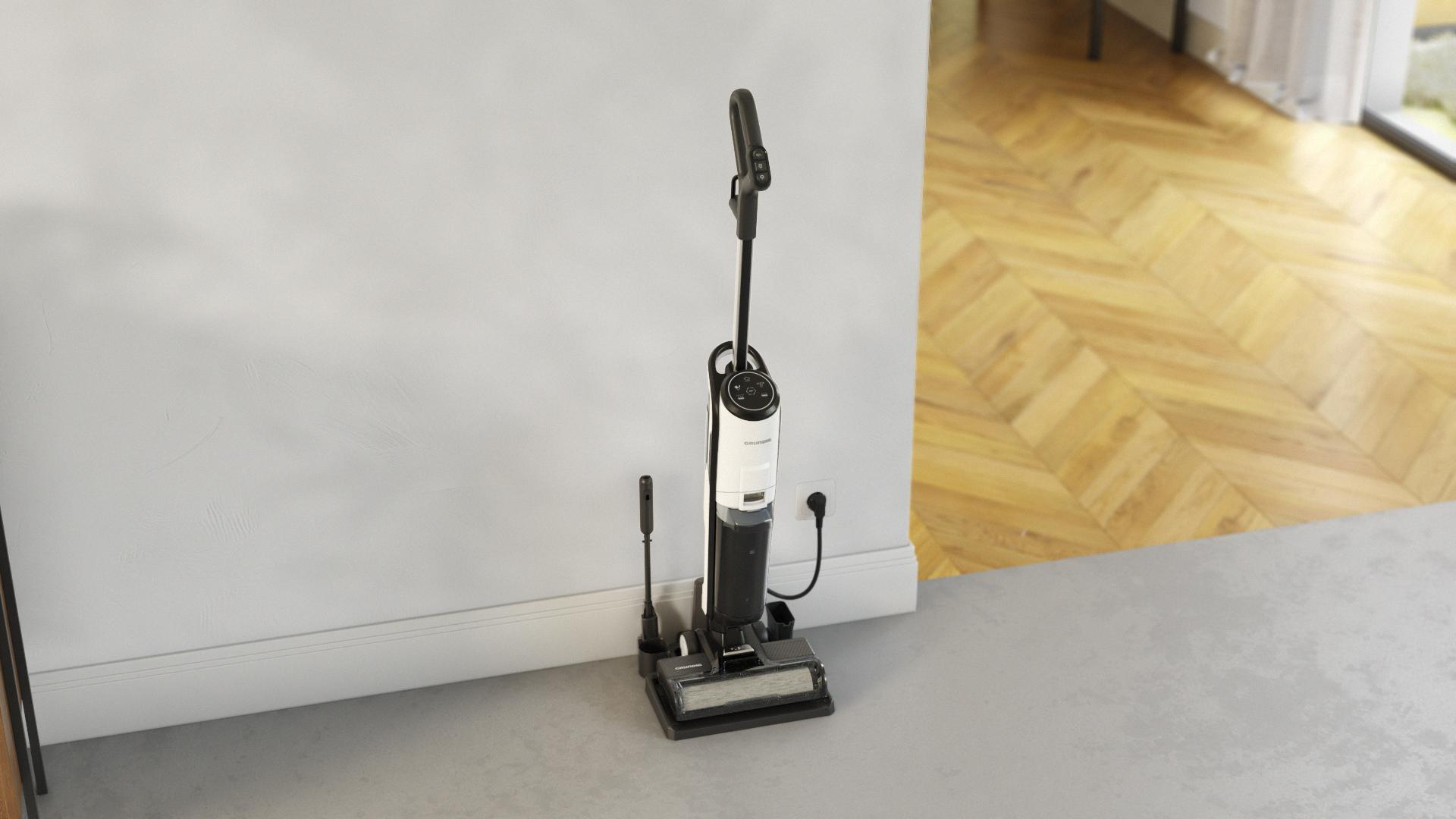 Ein schnurloser Staubsauger und eine Ladestation in Schwarz-Weiß auf einem grauen Betonboden. Weiße Wand.