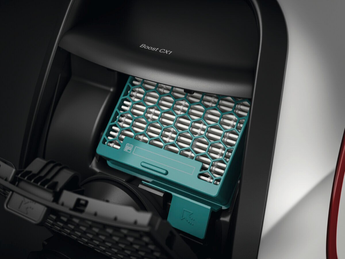 Zbliżenie komory odkurzacza z turkusowym filtrem. Komora jest czarna.