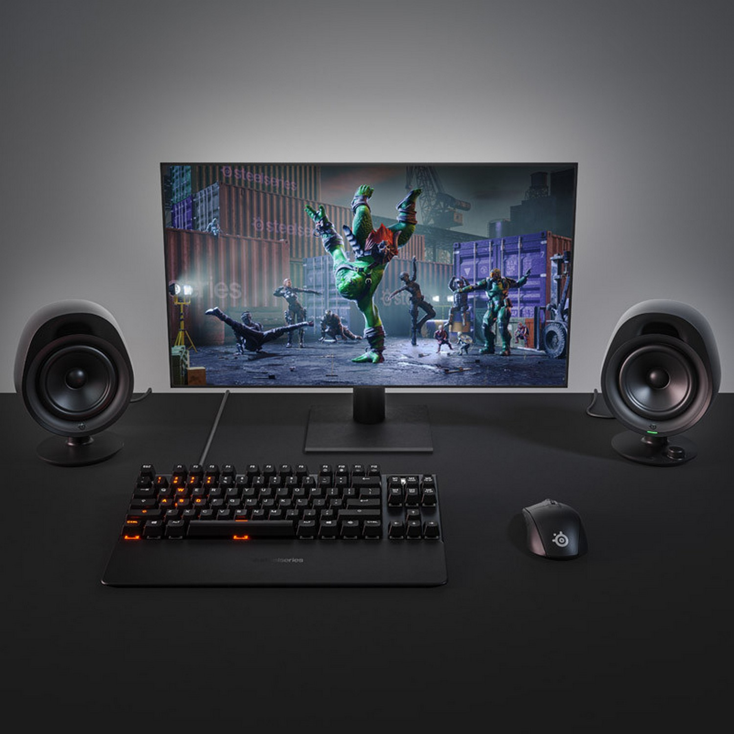 Gaming setup with a monitor displaying a game, keyboard, mouse, and speakers.