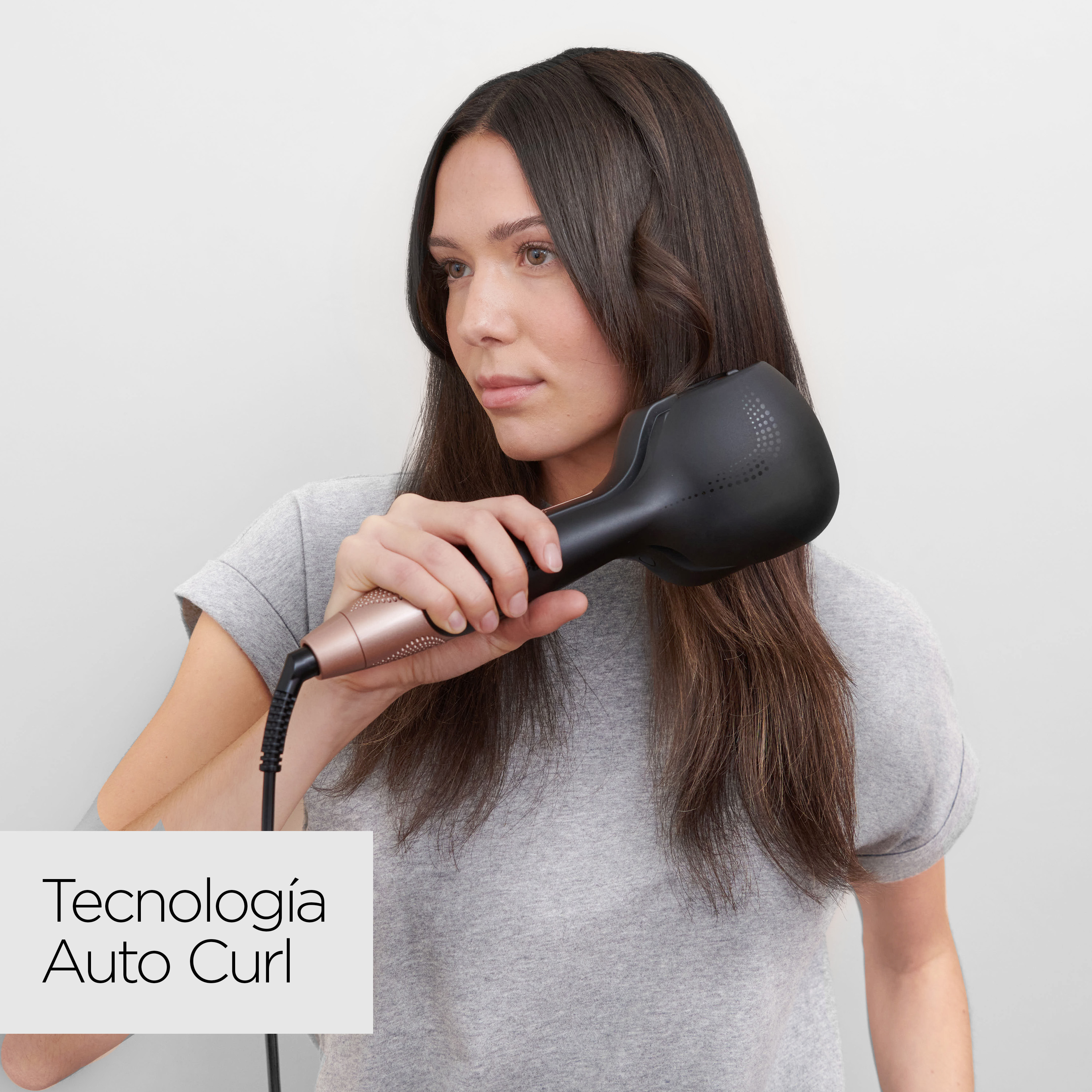 Una mujer se riza el pelo con un rizador automático negro y dorado. El texto dice 'Tecnología Auto Curl'.