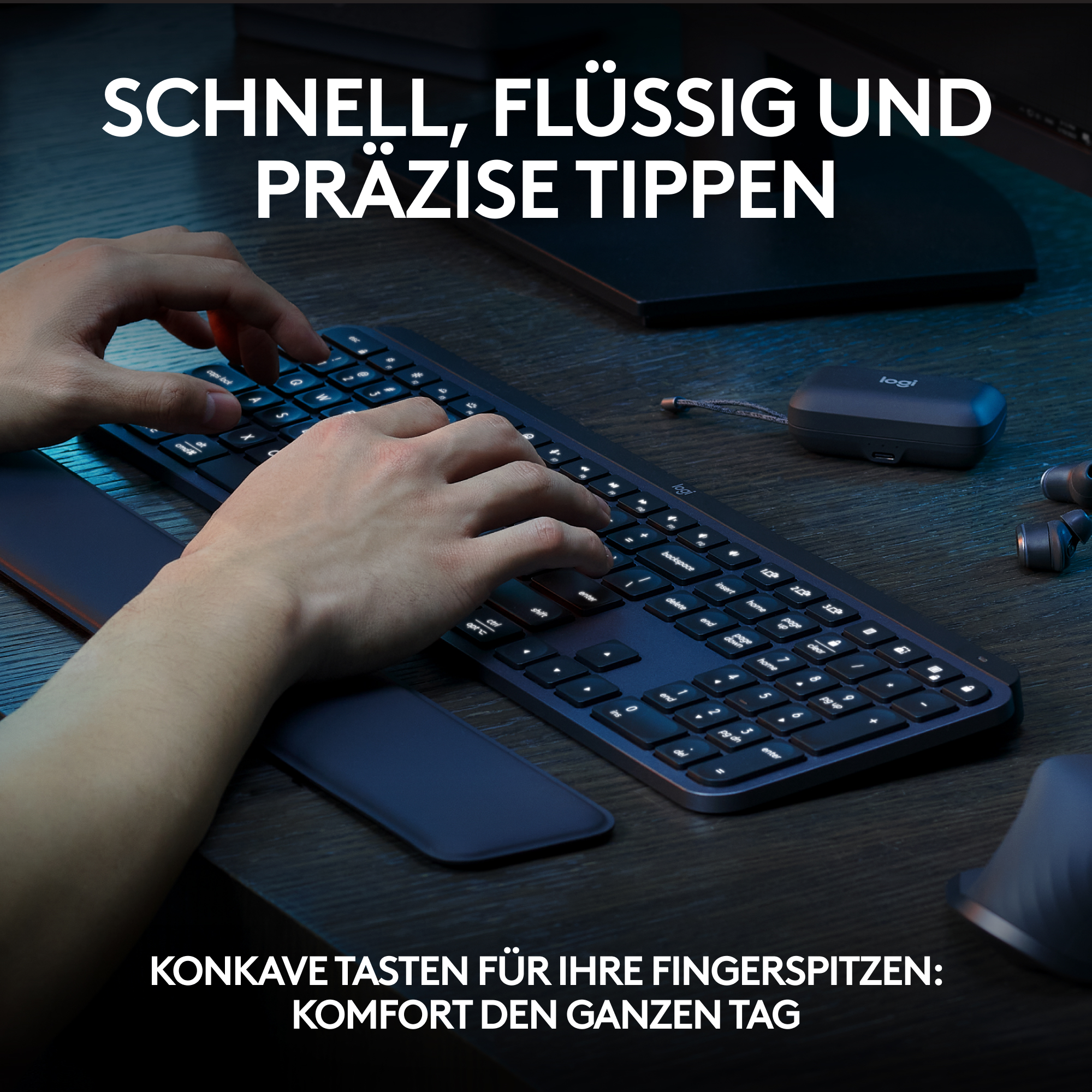 Person tippt auf einer dunklen Tastatur mit Handballenauflage. Dunkler Holztisch mit Maus und Kopfhörern.