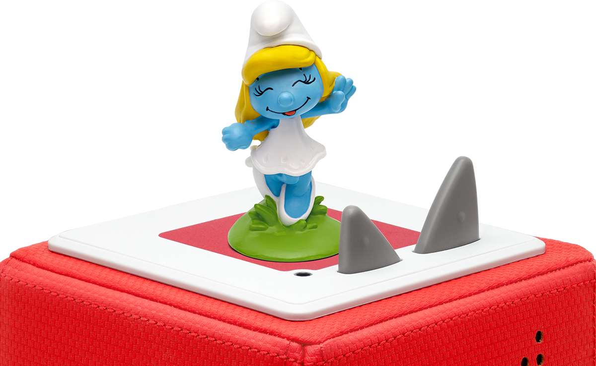 Eine Schlumpfine-Figur auf einer roten Box mit zwei Haifischflossen. Sie steht auf schwarzem Grund.