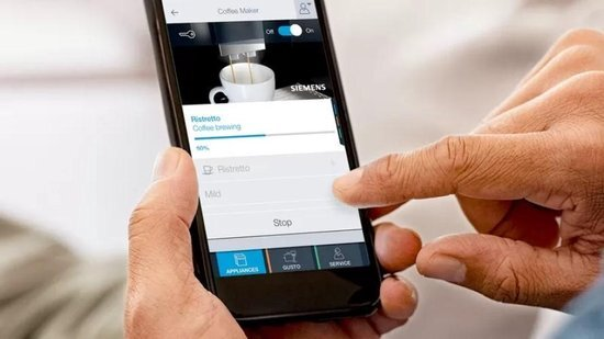 Ekran smartfona wyświetlający interfejs aplikacji do ekspresu do kawy, z interakcją dłoni.