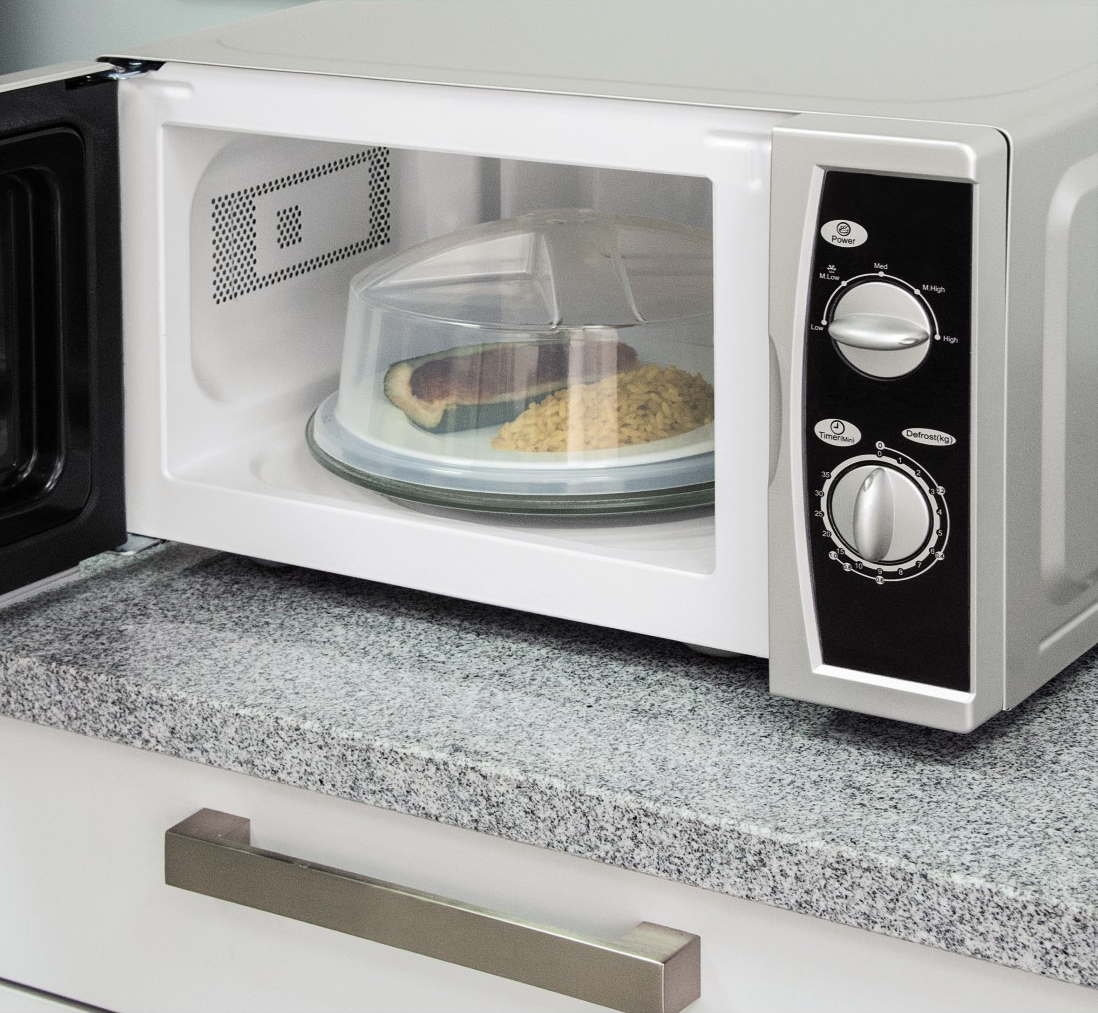 Un forno a microonde con la porta aperta. All'interno, un piatto coperto da un coperchio, con cibo.
