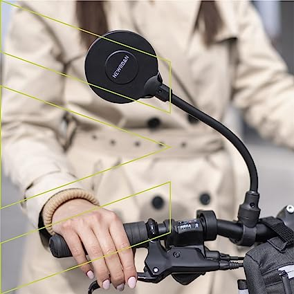 Die Hand einer Person an einem Fahrradlenker mit einem Rückspiegel. Der Spiegel ist rund und schwarz.