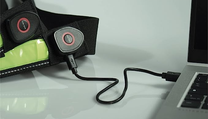 Luce nera e gialla con cavo USB collegato a un laptop. Superficie bianca nella scena.