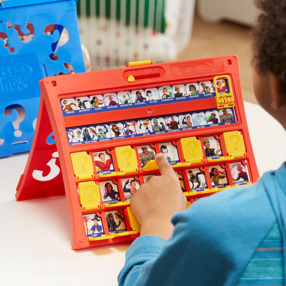 Die Hand eines Kindes zeigt auf ein Spielbrett von Guess Who mit Charakterkarten.