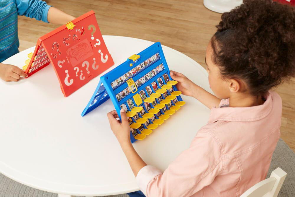 Zwei Kinder spielen ein Wer bin ich?-Spiel. Eines hält ein blaues Spiel, das andere ein rotes.