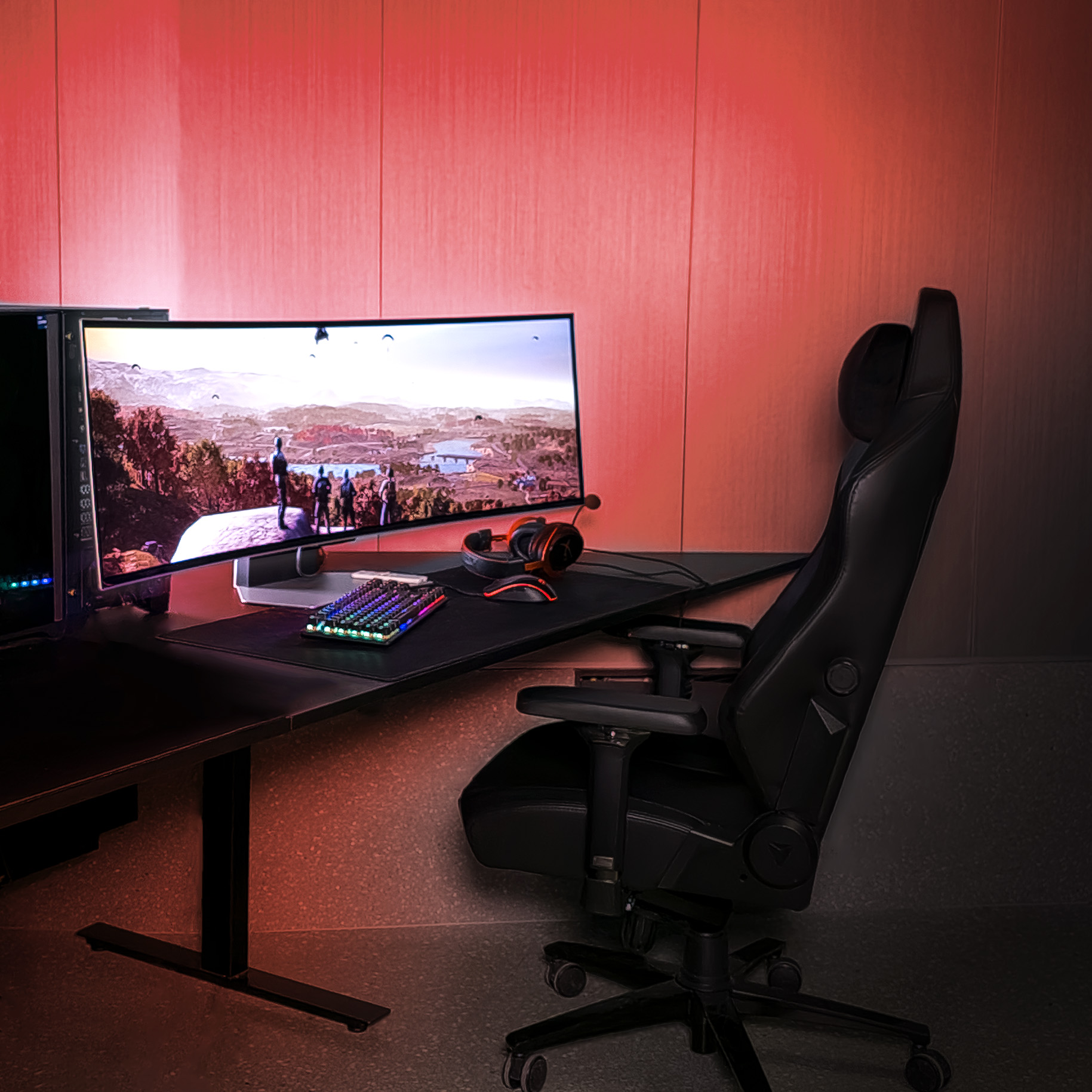 Gaming-Setup mit Monitor, Tastatur, Stuhl und Headset in einem dunklen Raum.