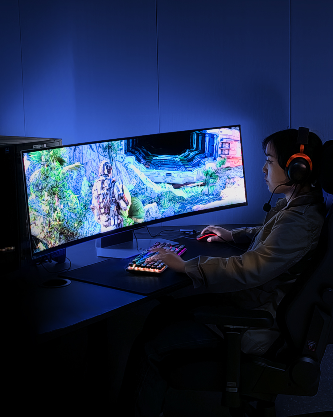 Eine Person spielt in einem dunklen Raum, mit einem Monitor, der eine Spielszene anzeigt.