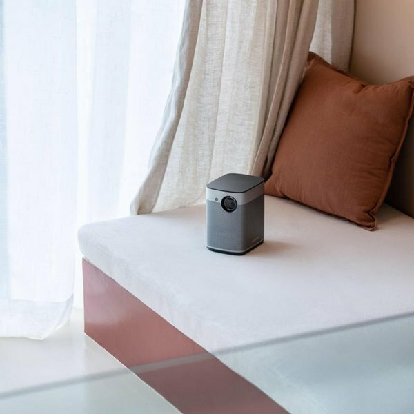 Mały, szary projektor na białej ławce przy oknie.