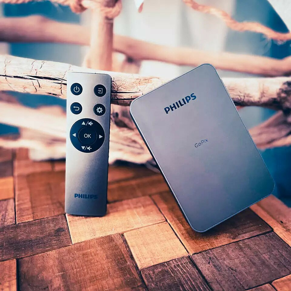 Pilot Philips i urządzenie Philips GoPix są wyświetlane na drewnianej powierzchni.