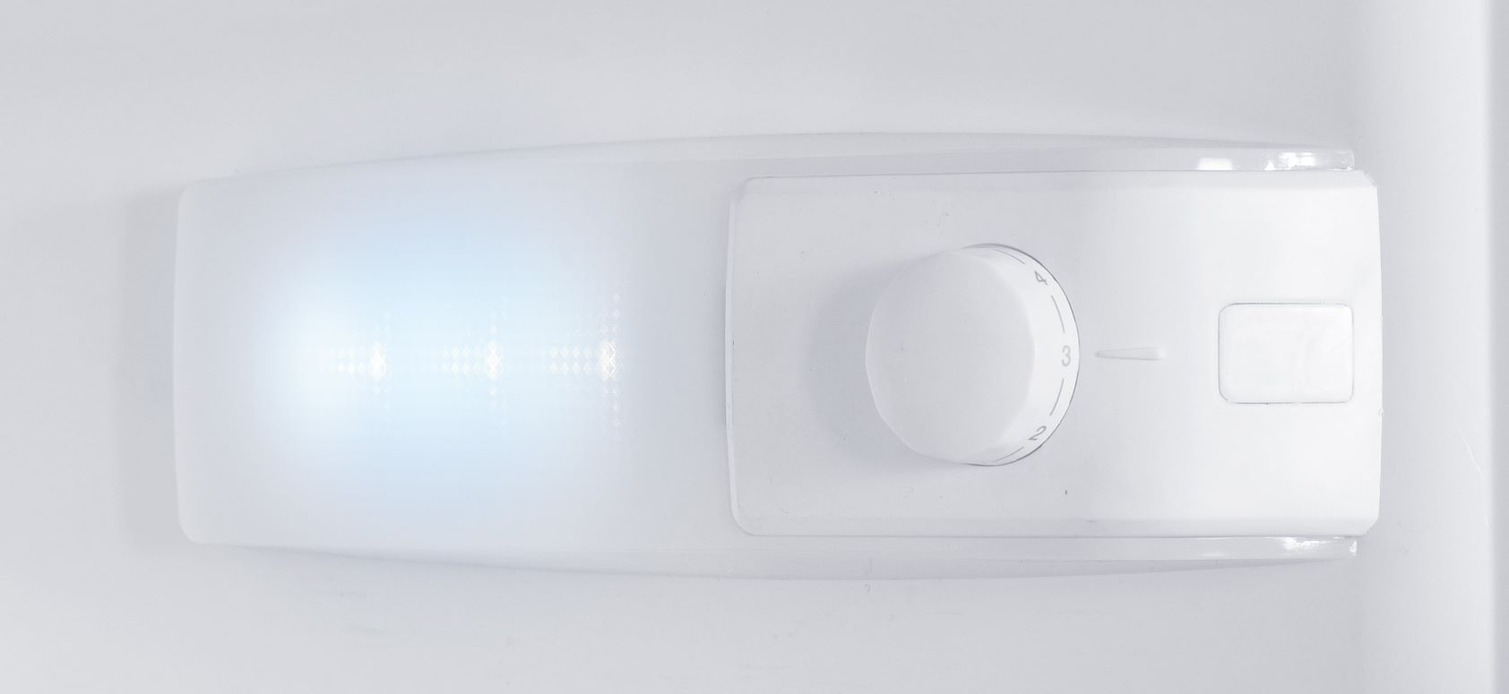 Interior de refrigerador blanco con luz y dial de control de temperatura.