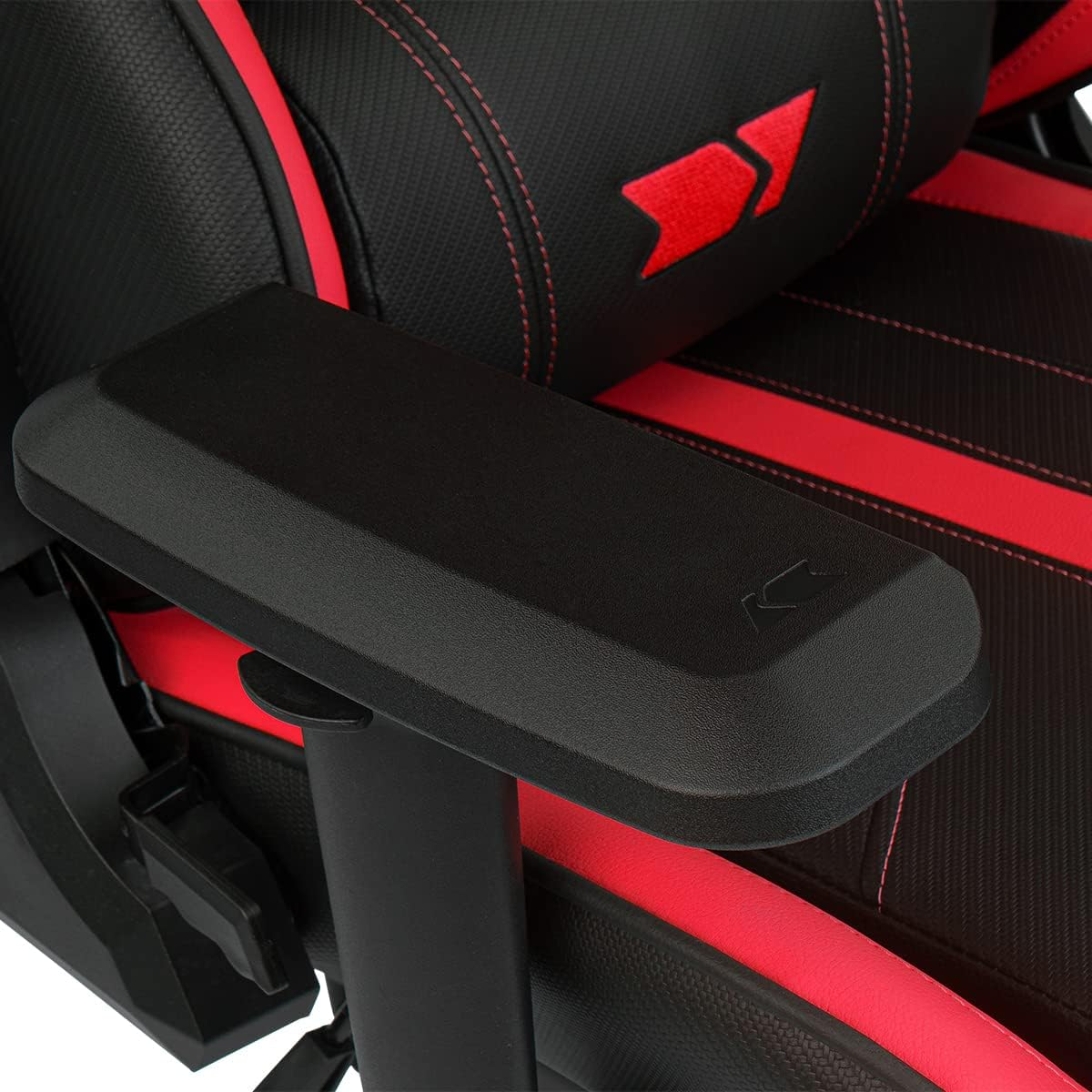 Primer plano de un reposabrazos negro de silla gaming con respaldo rojo y negro al fondo.