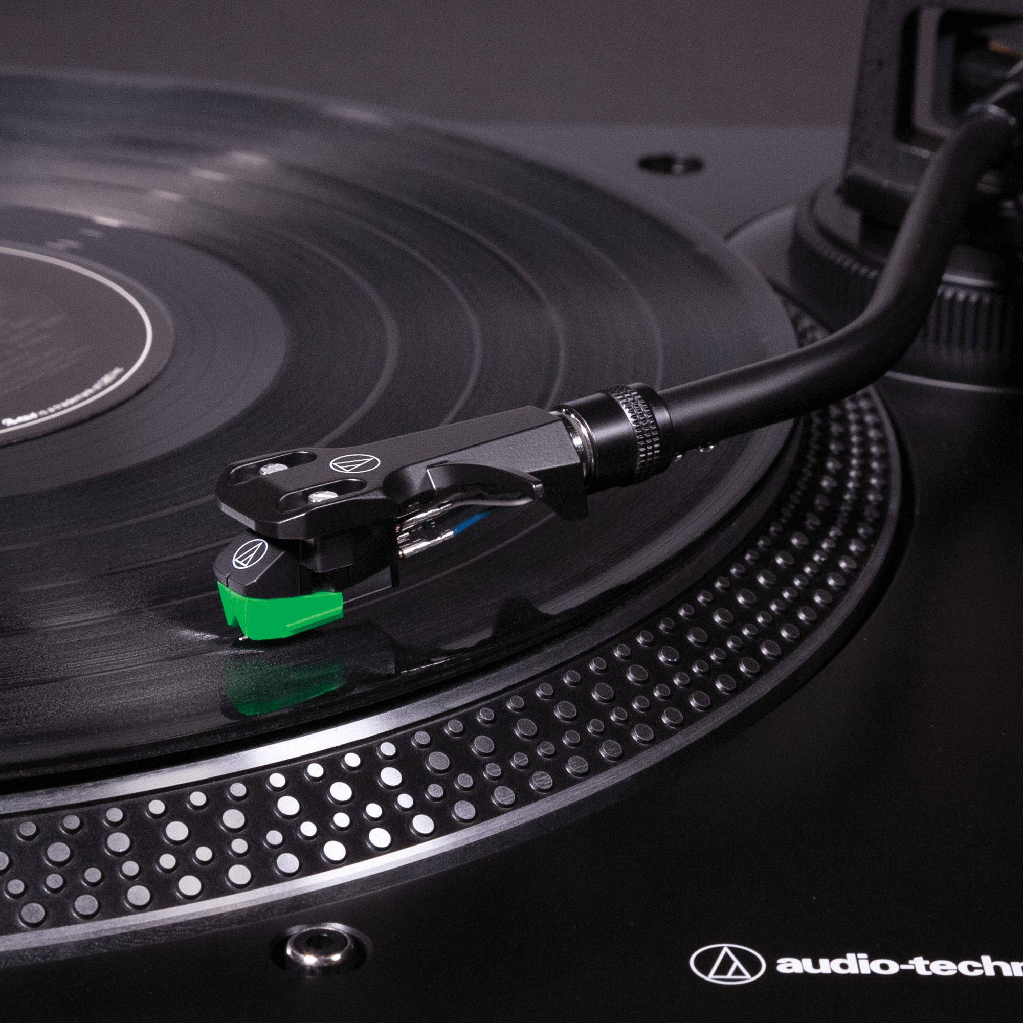 Közelkép egy fekete lemezjátszóról vinyl lemezzel. A tű zöld, a márka audio-technica.