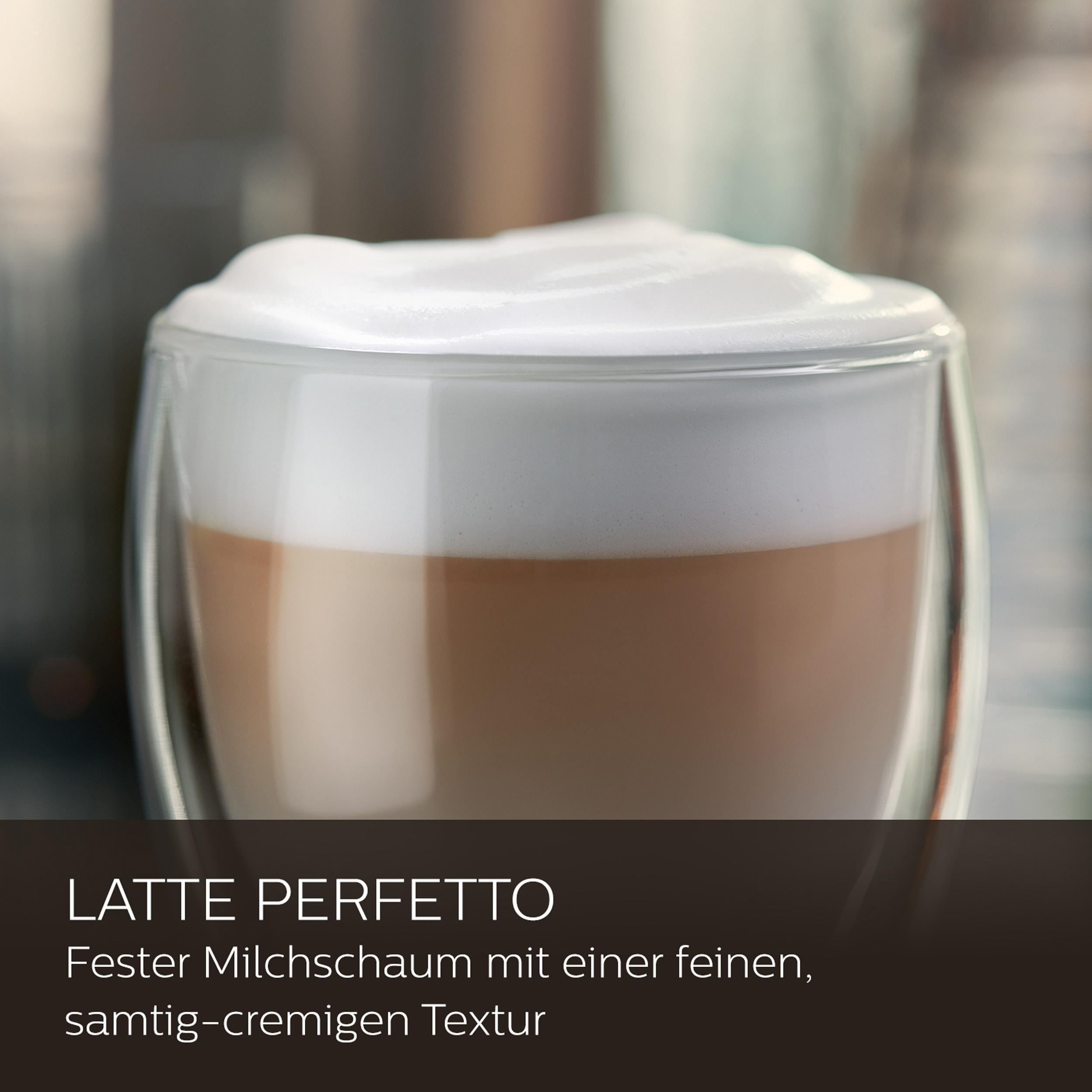 Latte in einem klaren Glas mit schaumiger Milch oben drauf.