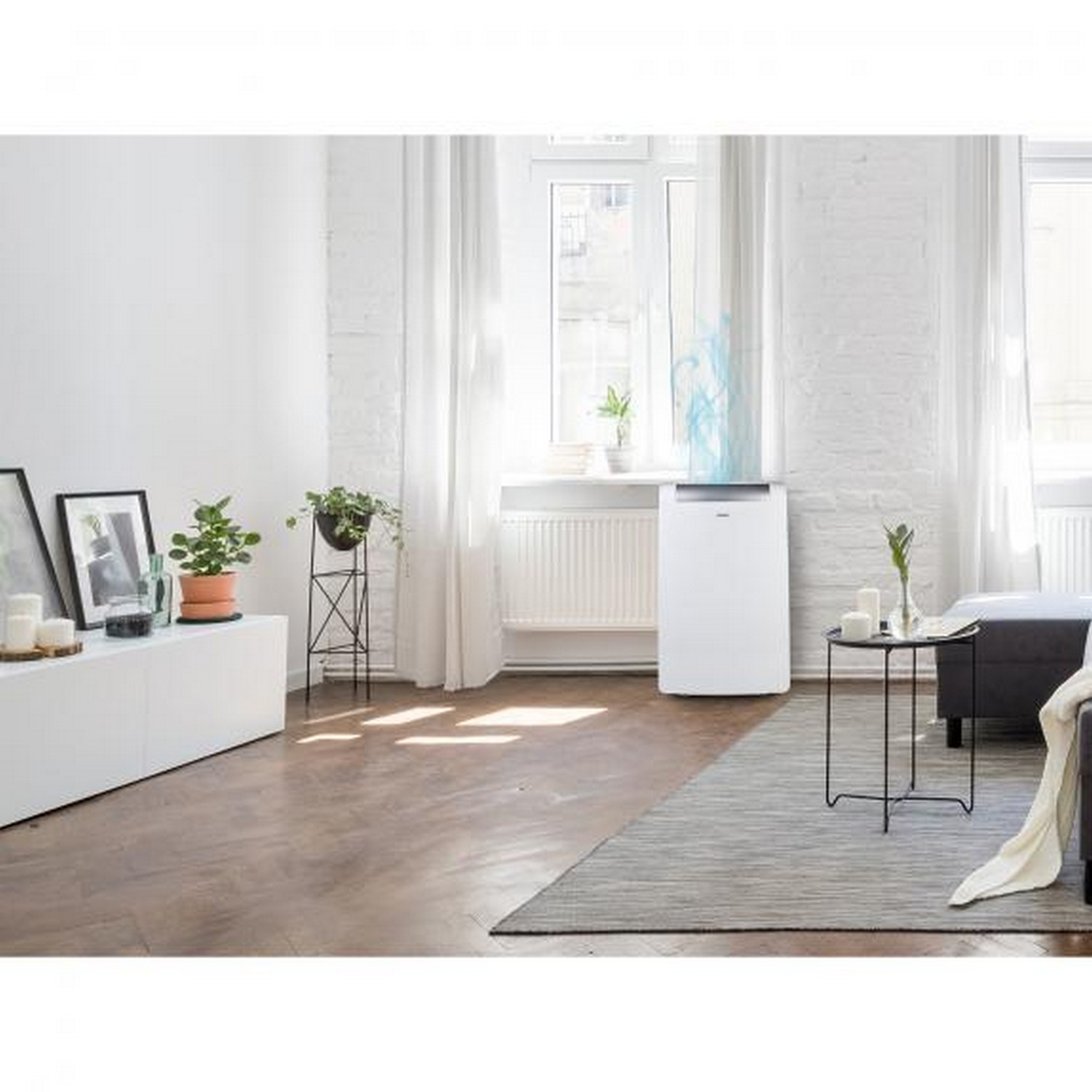 Salon avec murs blancs, purificateur d'air blanc, tapis gris, fenêtre et plantes.