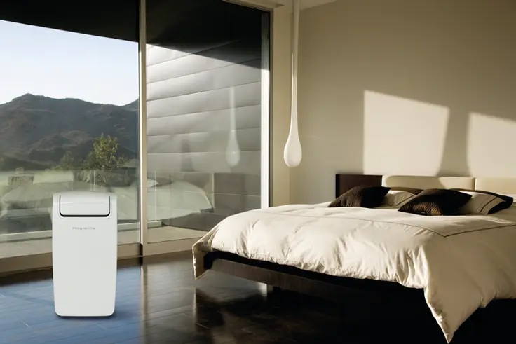 Een moderne slaapkamer met een witte luchtreiniger naast een groot raam en een opgemaakt bed.