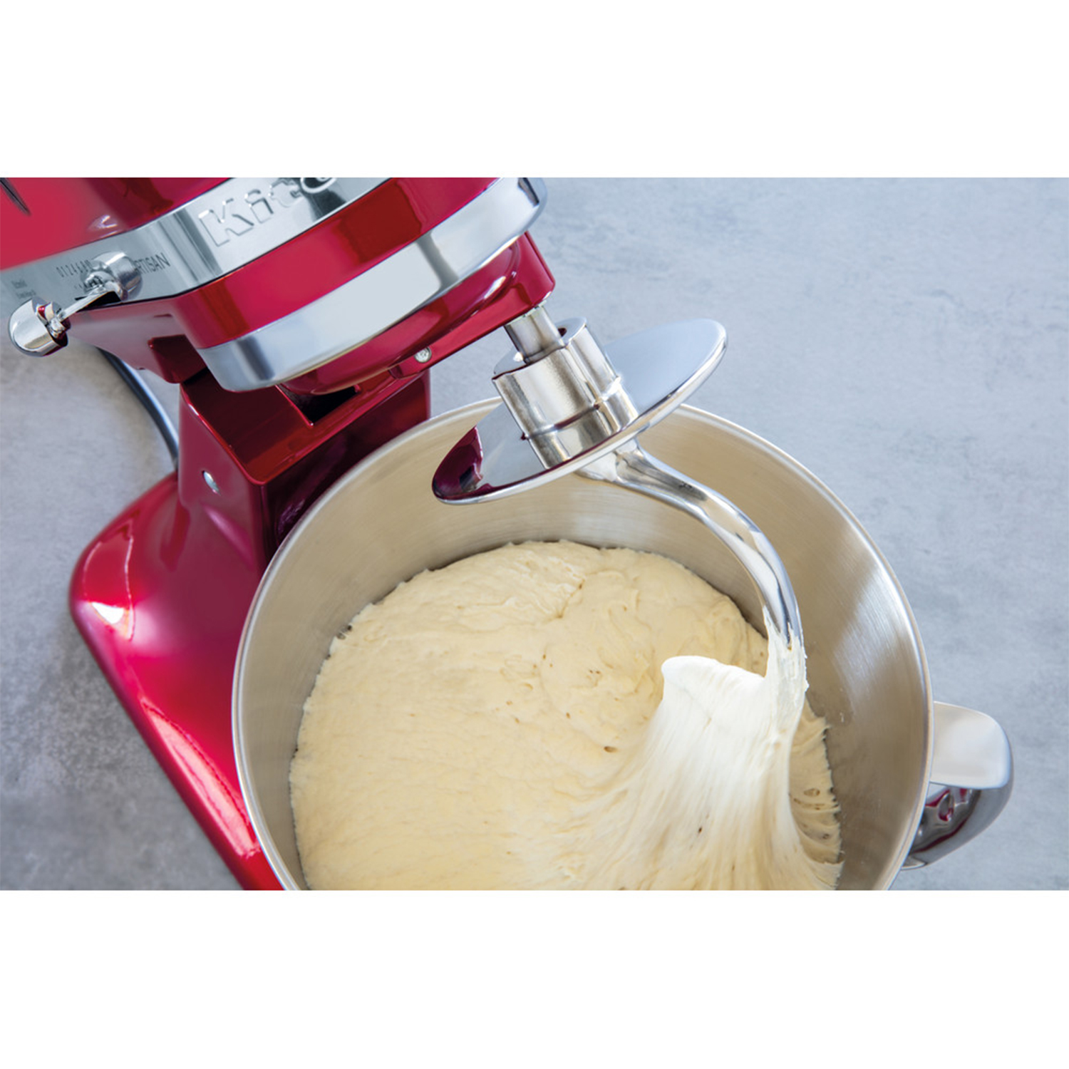 Frullatore KitchenAid rosso che mescola l'impasto in una ciotola di metallo. L'impasto è bianco.