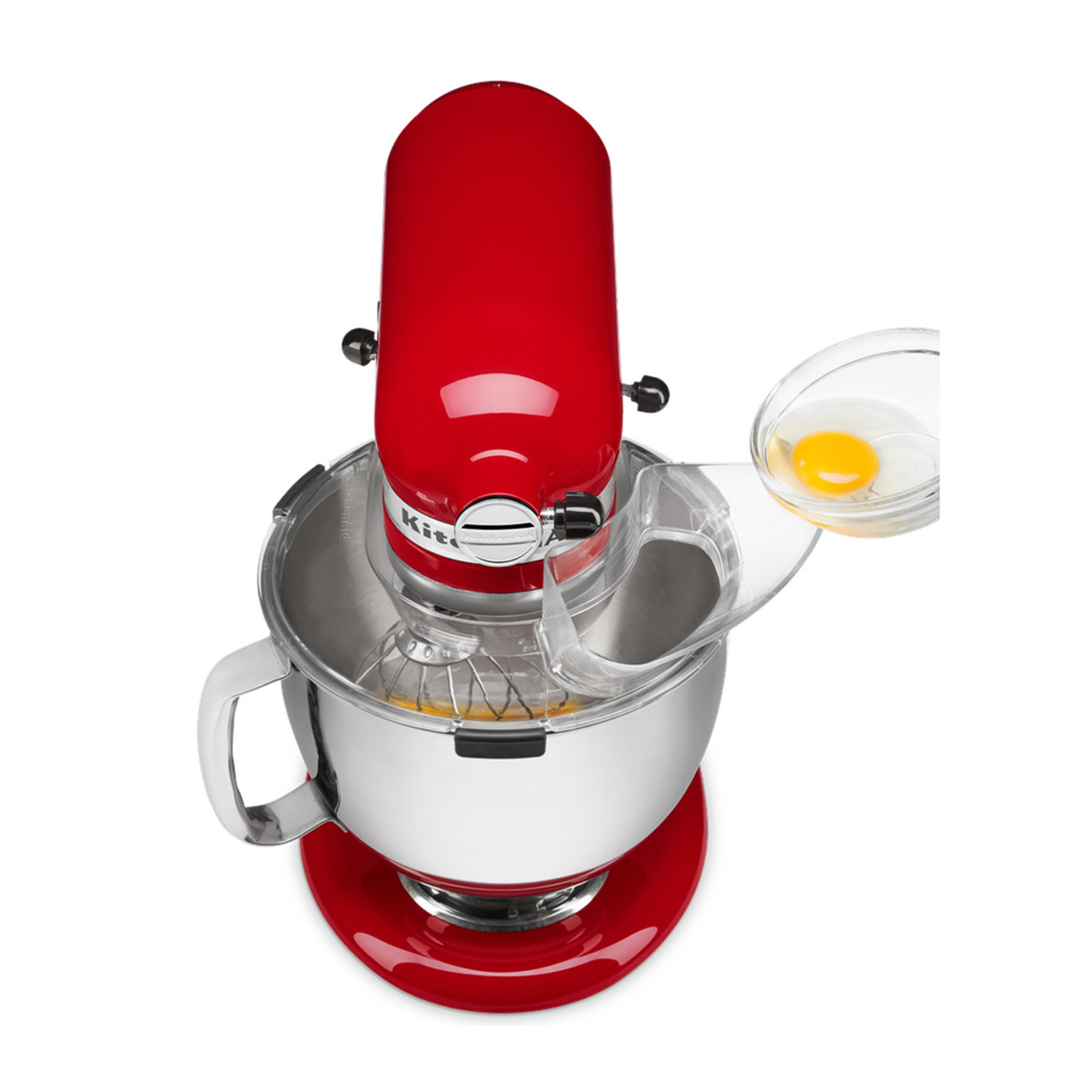 Frullatore KitchenAid rosso con ciotola, accessorio frusta. Uovo crudo versato nella ciotola dall'alto.